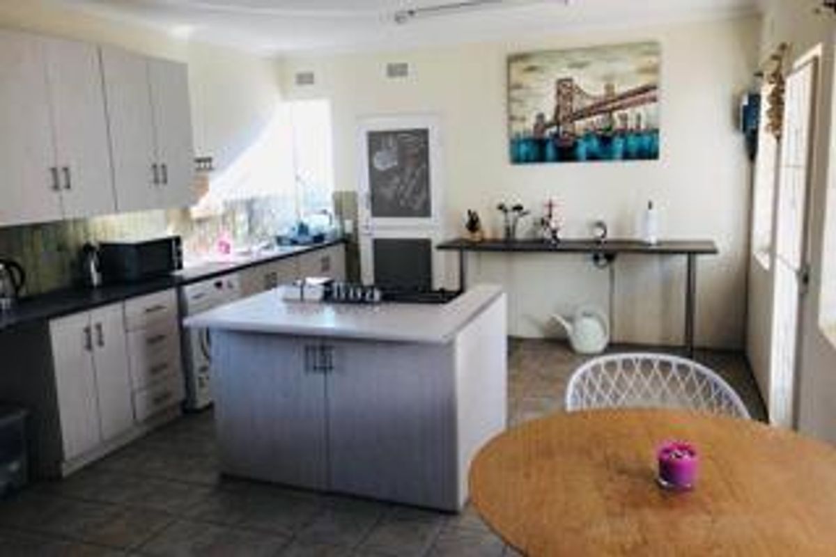 A functional kitchen featuring white cabinetry, a central island, tiled flooring, and direct access to an exterior door.