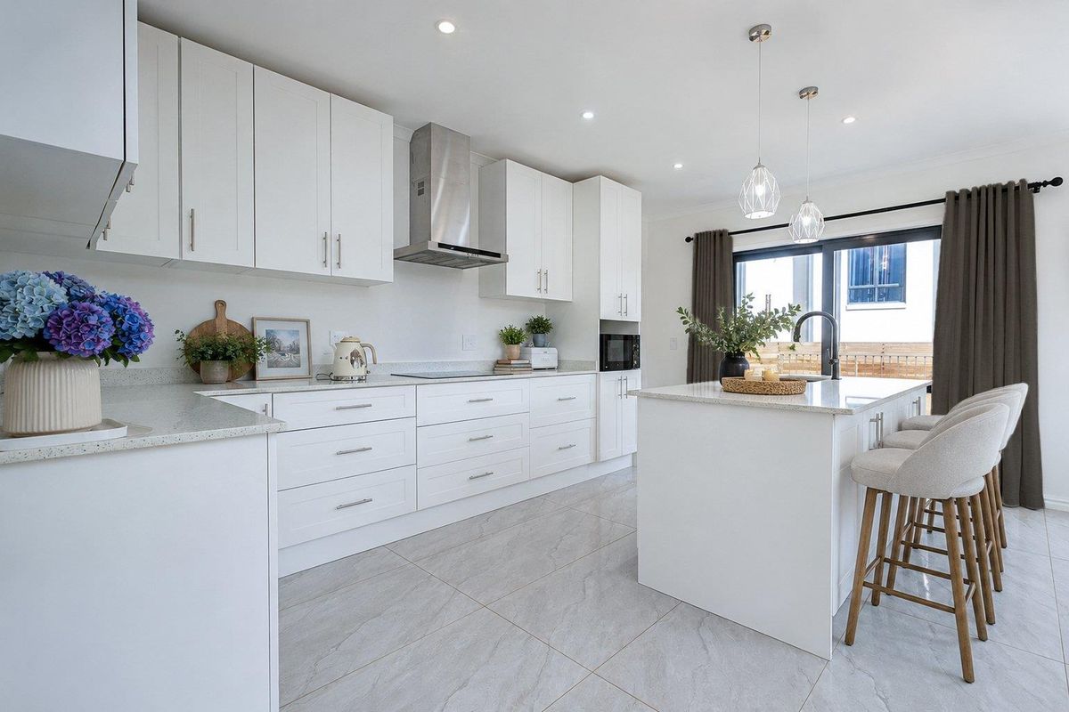 Modern kitchen featuring white cabinetry, stone benchtops, a central island, stainless steel appliances, and tiled flooring with direct access to the outdoor area.
