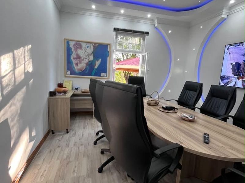 Modern office boardroom featuring a custom recessed ceiling with blue LED accent lighting, laminate flooring, and integrated wall design elements.