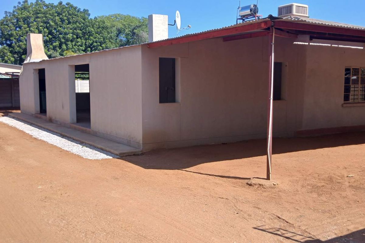 Rear view of the property featuring a covered patio area, corrugated metal roofing, and a solar water heater installation.