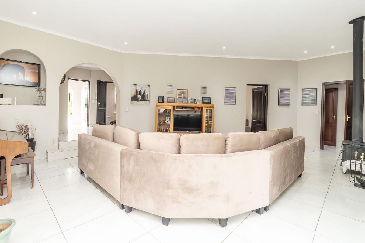 Spacious living room featuring tiled flooring, recessed ceiling lighting, a built-in fireplace, and arched architectural transitions leading to adjacent areas.