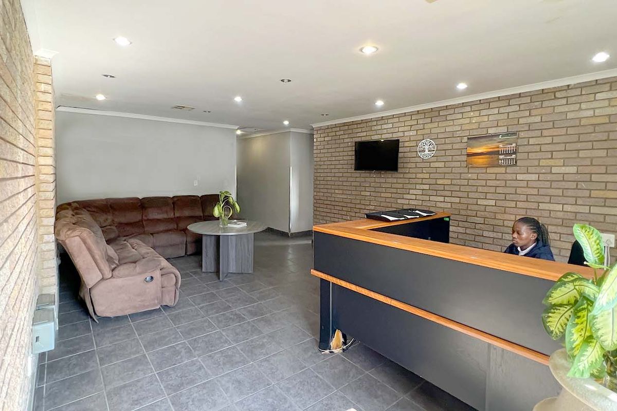 Reception area featuring exposed brick walls, tiled flooring, and a built-in reception desk, suitable for professional office or industrial administrative use.