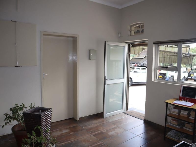 A functional office entrance area featuring tiled flooring, a glass-panelled door, and a transom window providing natural light.