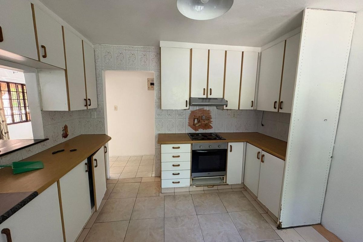 A functional kitchen featuring white cabinetry, laminate countertops, built-in oven, and gas hob, with tiled flooring and backsplash throughout.