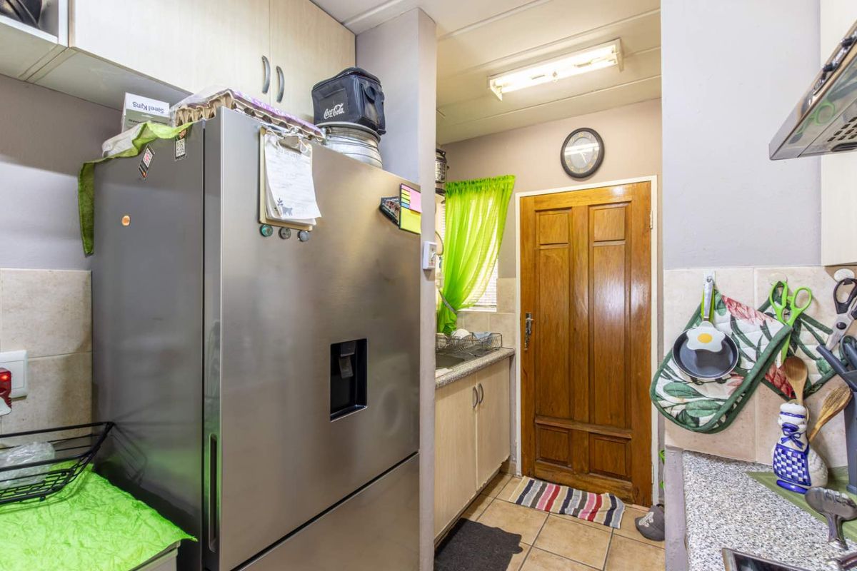 A functional kitchen area featuring built-in cabinetry, tiled splashbacks, and a solid timber door leading to the exterior.