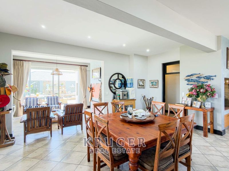 Spacious open-plan living and dining area featuring tiled flooring, recessed lighting, and large sliding doors leading to an outdoor patio space.