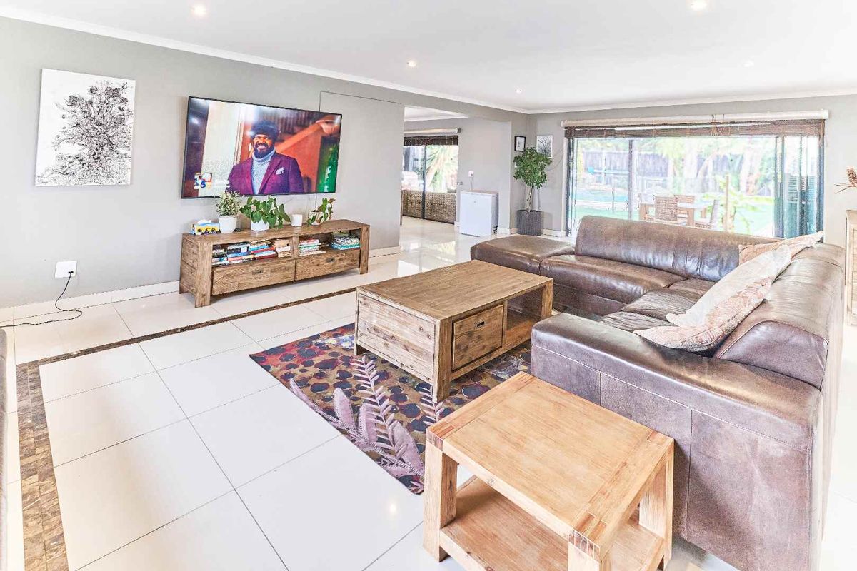 Spacious living room featuring large format tiled flooring, recessed downlighting, and sliding glass doors providing access to the outdoor area.