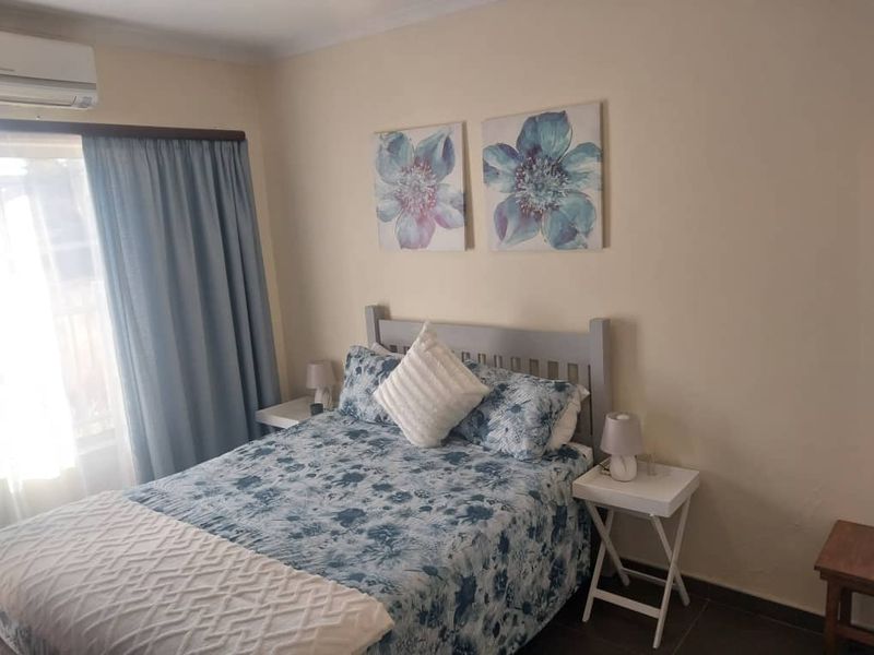 A functional bedroom featuring tiled flooring and a wall-mounted split-system air conditioning unit.