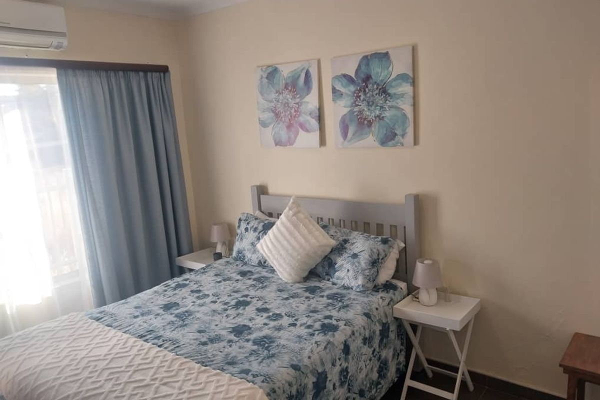 A functional bedroom featuring tiled flooring and a wall-mounted split-system air conditioning unit.
