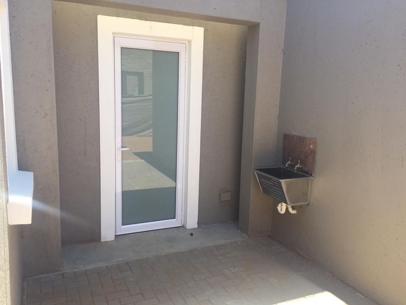 A functional outdoor utility area featuring a stainless steel sink and paved flooring, providing convenient access to the property's exterior.
