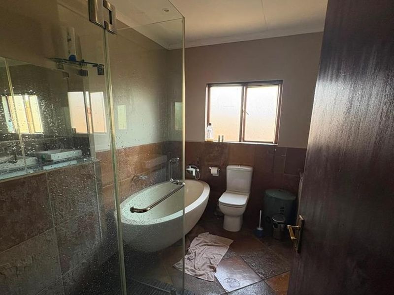 A bathroom featuring a freestanding bathtub, a glass-enclosed shower, and tiled finishes throughout, offering a functional layout with natural light.