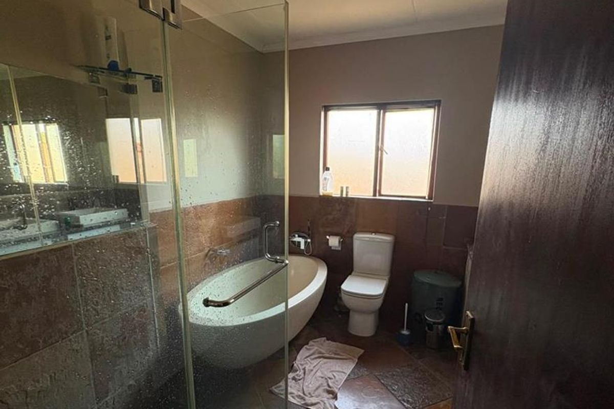 A bathroom featuring a freestanding bathtub, a glass-enclosed shower, and tiled finishes throughout, offering a functional layout with natural light.