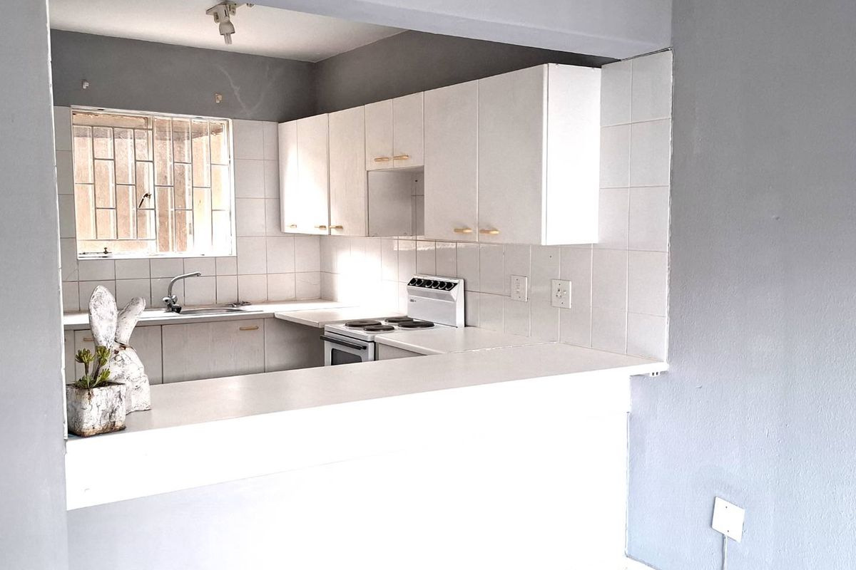 A functional kitchen featuring white cabinetry, a breakfast bar, tiled backsplash, and a built-in stove, offering a clean and practical layout.