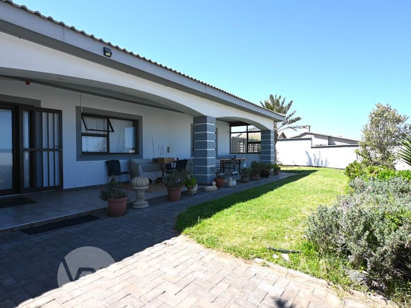 A spacious covered patio area featuring tiled flooring and direct access to the rear garden and lawn.