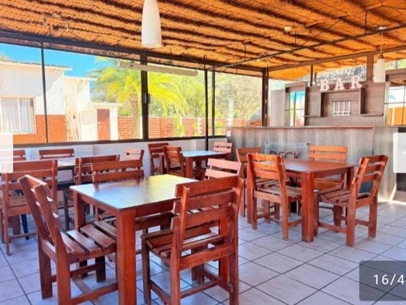 Covered outdoor patio area featuring a built-in bar, thatched roofing, and tiled flooring, suitable for entertainment and social gatherings.