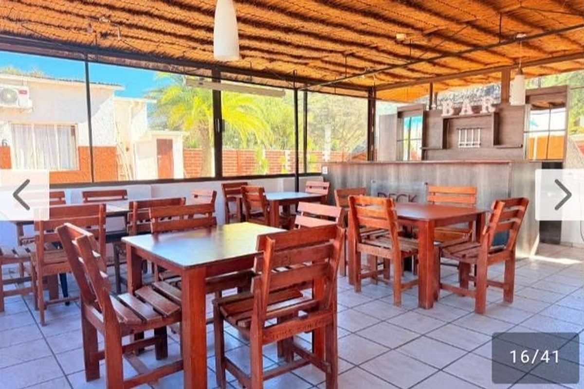 Covered outdoor patio area featuring a built-in bar, thatched roofing, and tiled flooring, suitable for entertainment and social gatherings.