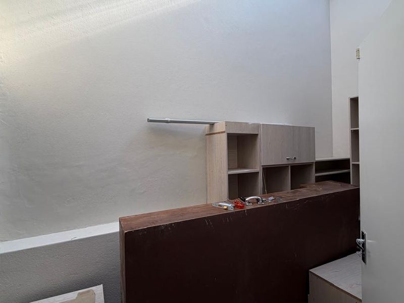 An office space featuring a built-in reception counter and cabinetry, illuminated by a skylight, currently in a state of incomplete installation.