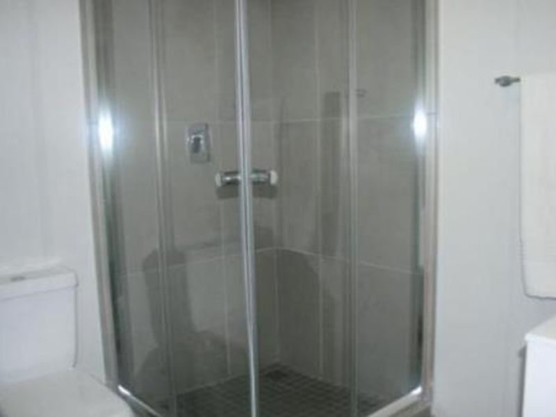 A functional bathroom featuring a glass-enclosed shower, a standard toilet, and a wall-mounted towel rail.