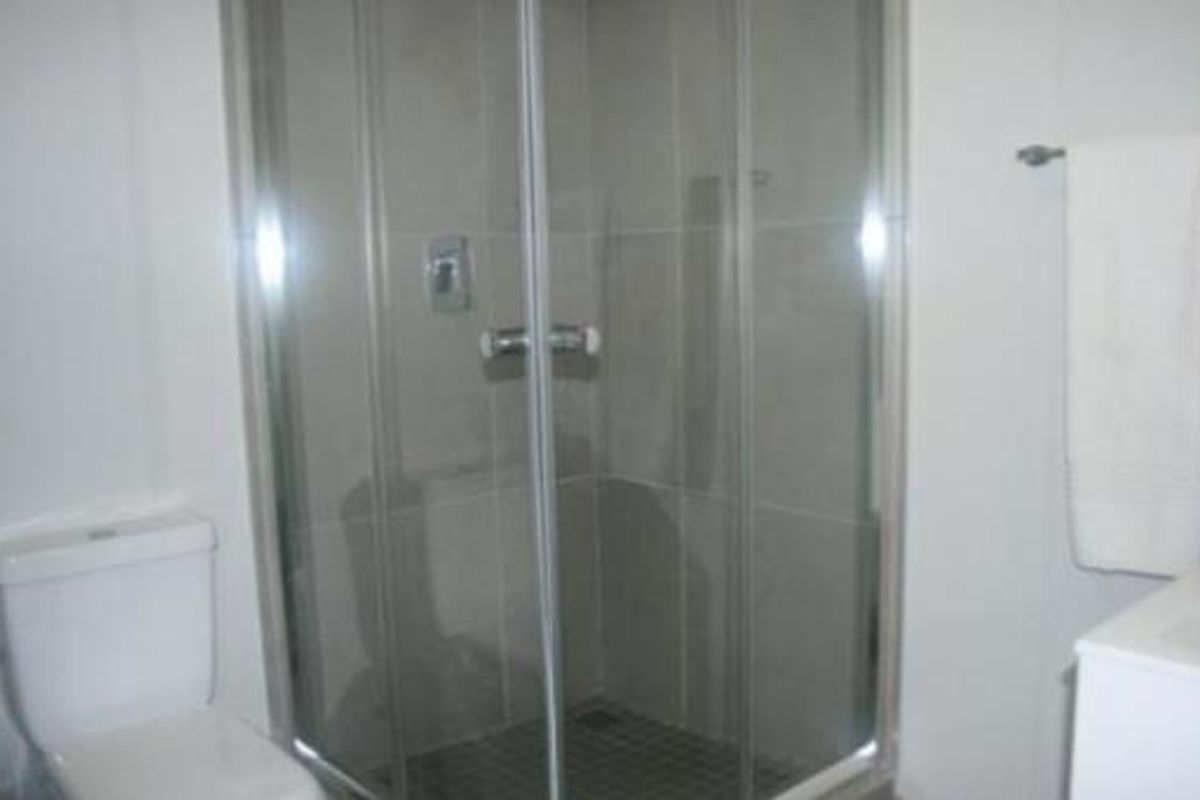 A functional bathroom featuring a glass-enclosed shower, a standard toilet, and a wall-mounted towel rail.