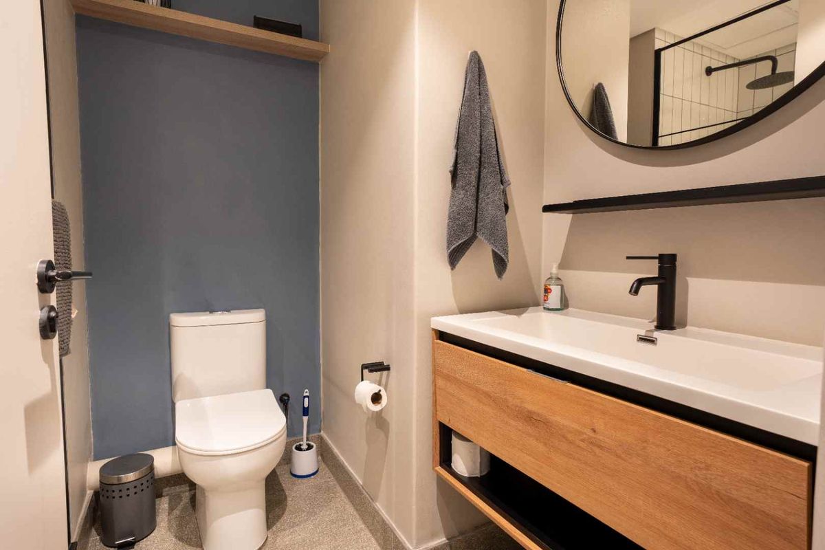 Modern bathroom featuring a wood-finish vanity with integrated sink, matte black fixtures, and a clean, contemporary design aesthetic.