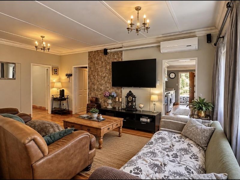 A comfortable living room featuring a stone-clad feature wall, hardwood flooring, and a split-system air conditioner, with access to adjacent rooms.