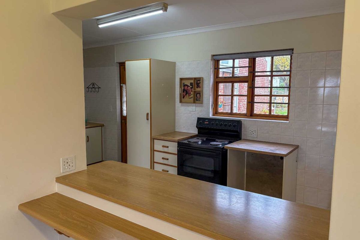 A functional kitchen featuring a breakfast bar, built-in cabinetry, and a freestanding stove, with a window providing natural light.
