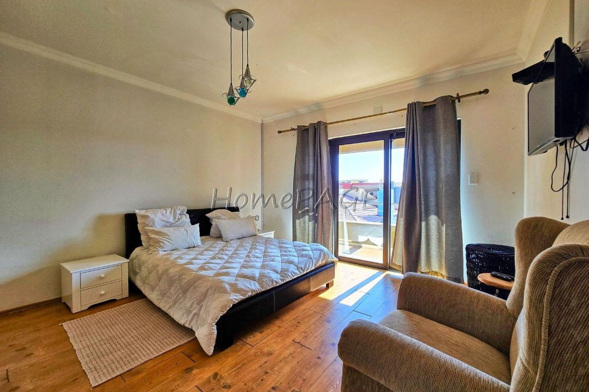 A bedroom featuring wood-look flooring, a ceiling light fixture, and sliding glass doors leading to an outdoor balcony.