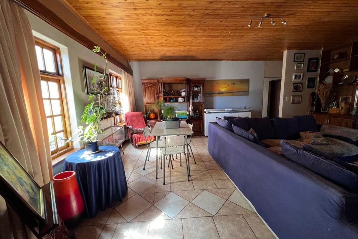Spacious living area featuring tiled flooring, large timber-framed windows, and a distinctive timber-clad ceiling, offering a warm and traditional aesthetic.