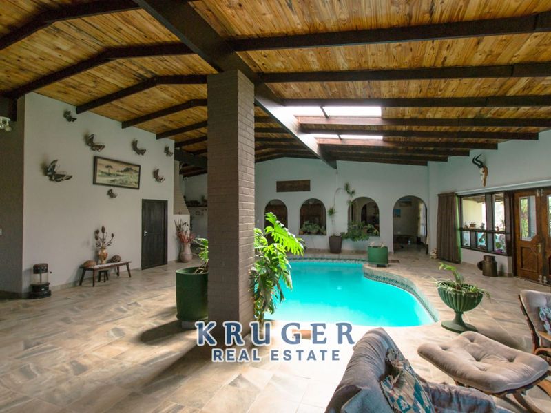 Indoor swimming pool area featuring a vaulted timber-beamed ceiling, skylights, and tiled flooring, creating a unique entertainment space.