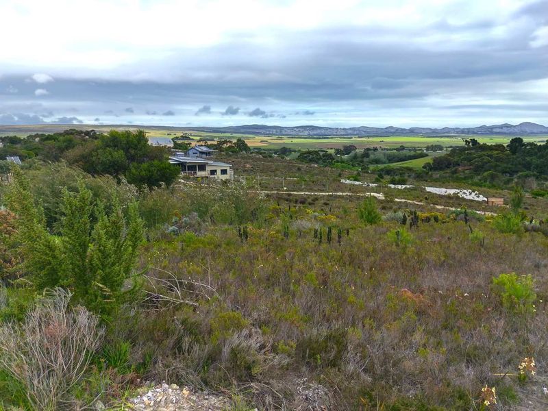 A wide-angle view of the vacant residential land, showcasing the natural landscape, surrounding vegetation, and distant mountain scenery.
