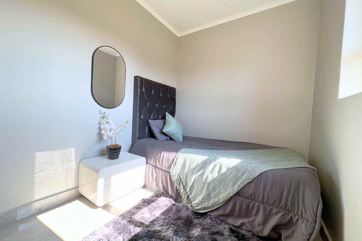 A well-lit bedroom featuring neutral wall tones, tiled flooring, and a coved ceiling, providing a clean and comfortable living space.