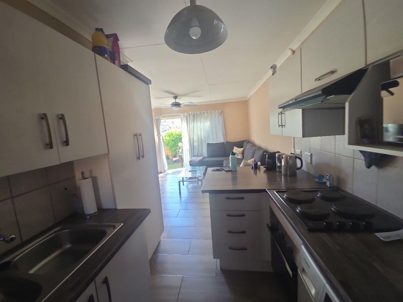 Open-plan kitchen and living area featuring tiled flooring, built-in cabinetry, and direct access to the rear patio and garden.
