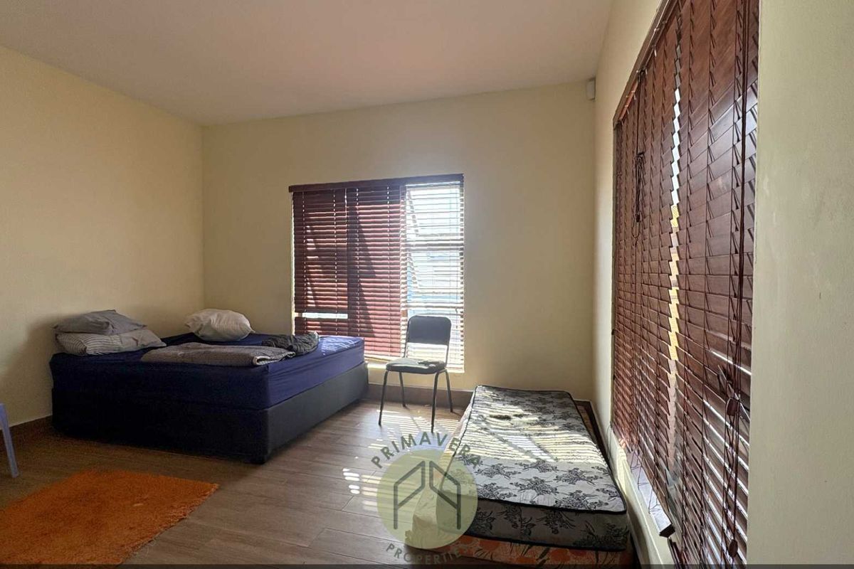 A bedroom featuring tiled flooring and wooden venetian blinds on the windows.
