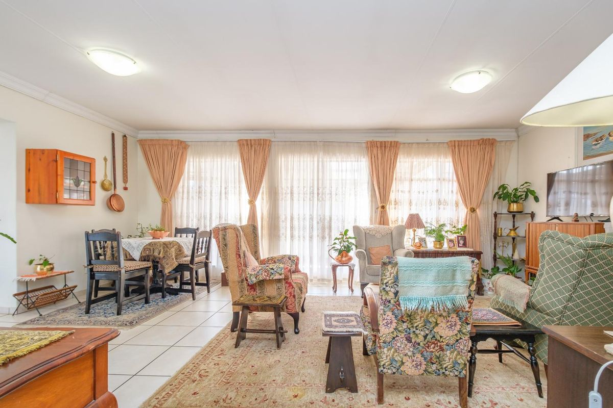 A spacious living and dining area featuring tiled flooring and large sliding glass doors that provide ample natural light.
