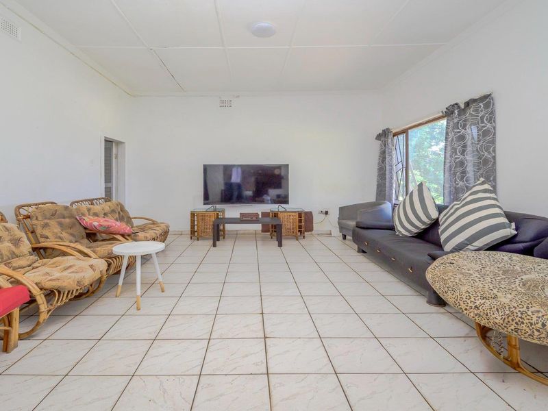 Spacious living room featuring neutral tiled flooring and a clean, minimalist layout, offering a versatile space for comfortable family living.