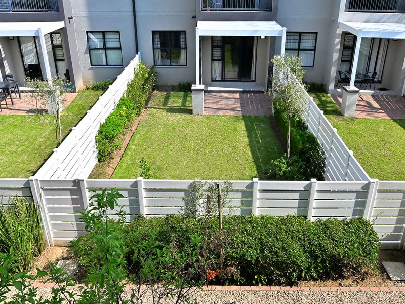 A well-maintained private rear garden featuring a paved patio, pergola, and neat white timber fencing, providing a pleasant outdoor living space.