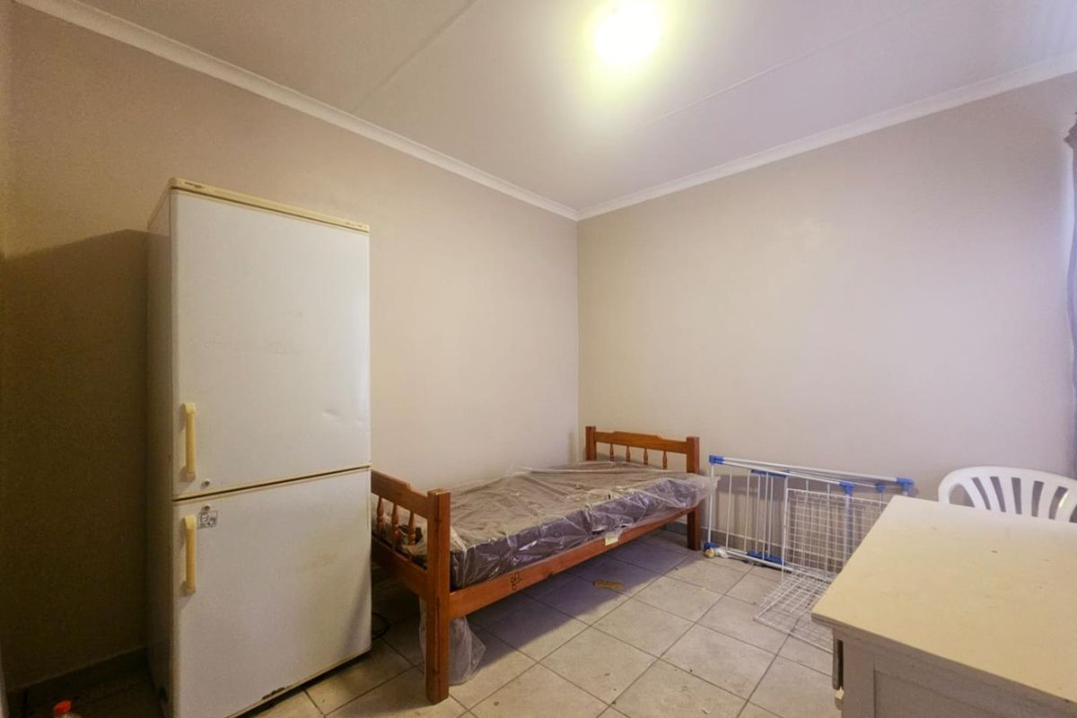 A basic bedroom space featuring tiled flooring and neutral wall finishes, suitable for renovation or functional use.