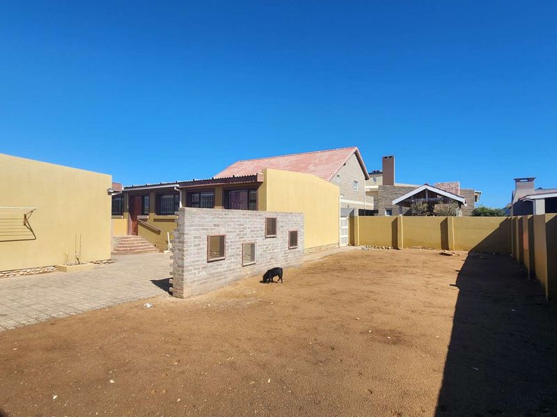 Spacious rear exterior area featuring a paved courtyard, brick feature wall, and perimeter boundary walls, offering potential for landscaping and outdoor living development.