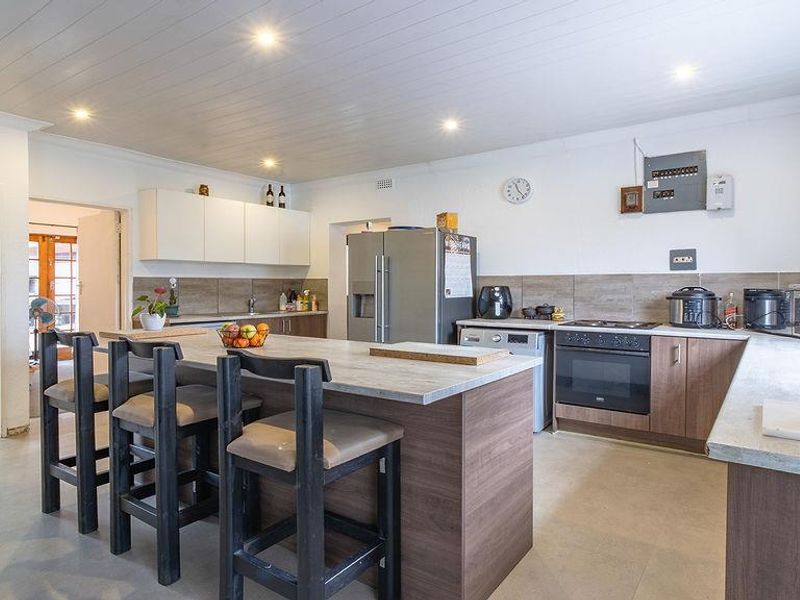 A functional kitchen featuring a central island, wood-look cabinetry, laminate countertops, and a built-in oven, with a clean tongue and groove ceiling finish.