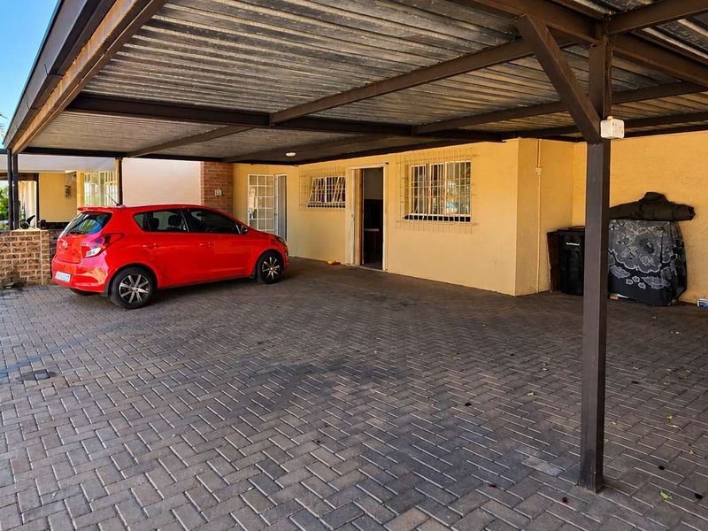 A covered carport area featuring paved flooring and secure access to the main dwelling.