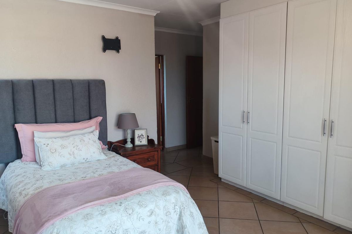 A well-maintained bedroom featuring neutral wall tones, tiled flooring, and ample built-in cupboard storage space.