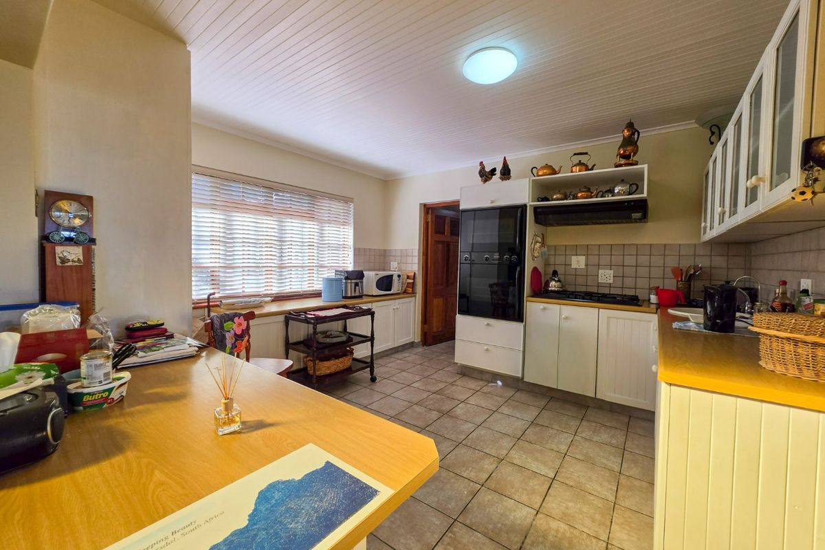 A functional kitchen featuring built-in oven, hob, extractor fan, tiled flooring, and ample cabinetry with a tiled backsplash and tongue and groove ceiling.
