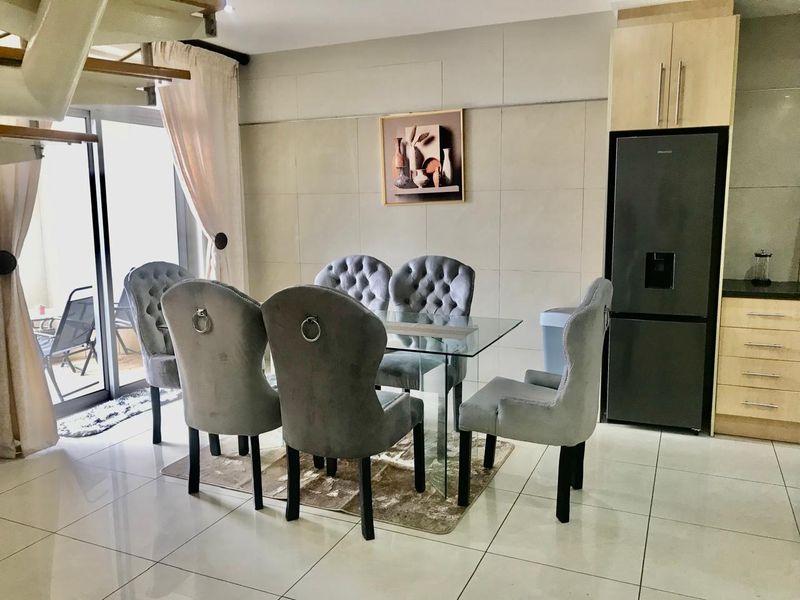 Open plan dining area featuring tiled floors, built-in kitchen cabinetry, and direct access to an outdoor patio through sliding glass doors.