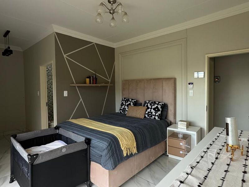 A well-maintained bedroom featuring tiled flooring, decorative wall paneling, and built-in storage, with direct access to an en-suite bathroom.