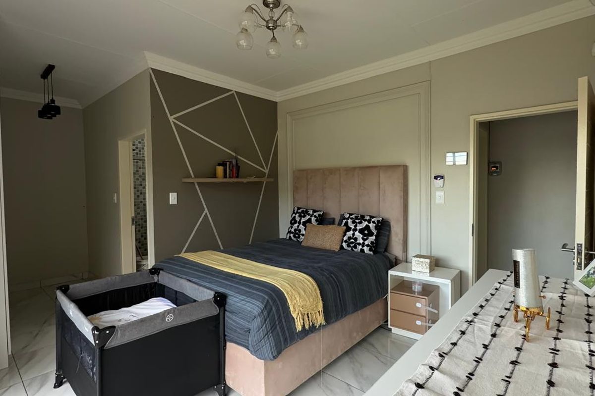 A well-maintained bedroom featuring tiled flooring, decorative wall paneling, and built-in storage, with direct access to an en-suite bathroom.