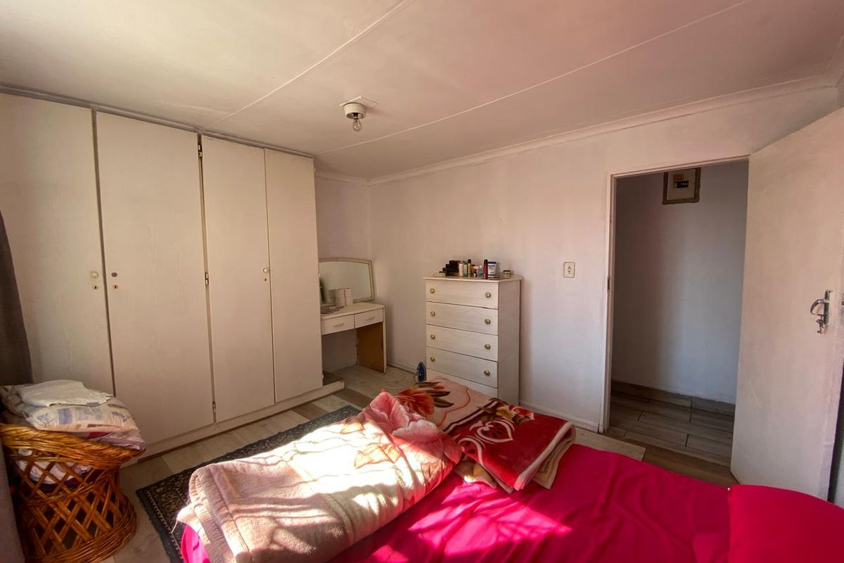 A bedroom featuring built-in cupboards and laminate flooring, offering a functional space with potential for cosmetic updates.