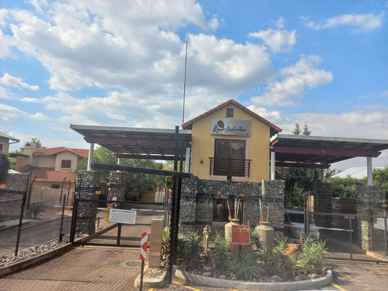 The secure entrance gatehouse of River Bushwillow Estate, featuring stone masonry pillars, metal roofing, and controlled access points.