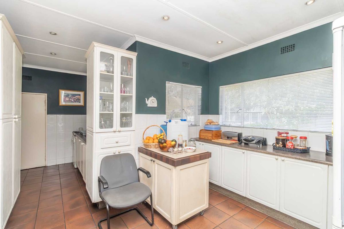 A functional kitchen featuring white cabinetry, tiled flooring, and a built-in display unit, offering a practical layout with ample counter space.