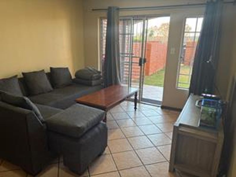 A living room featuring tiled flooring and a sliding glass door providing access to the outdoor area.