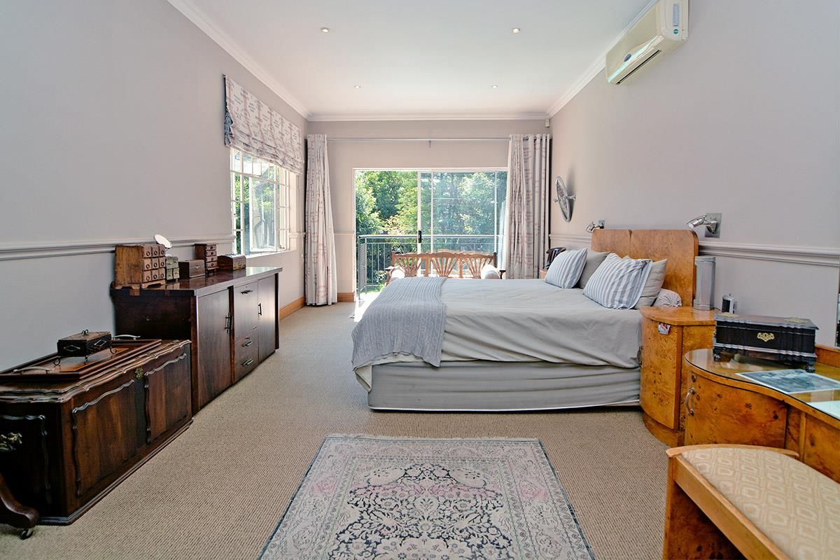 Spacious bedroom featuring neutral walls, carpeted flooring, recessed lighting, wall-mounted air conditioning unit, and sliding glass doors leading to a private balcony.